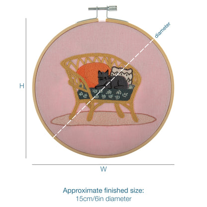 Embroidery hoop kit showing a stitched cat on wicker chair design
