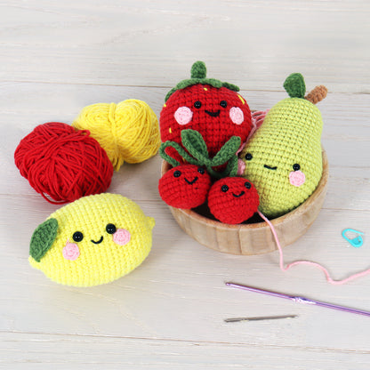 Four crocheted amigurumi fruits with smiley faces